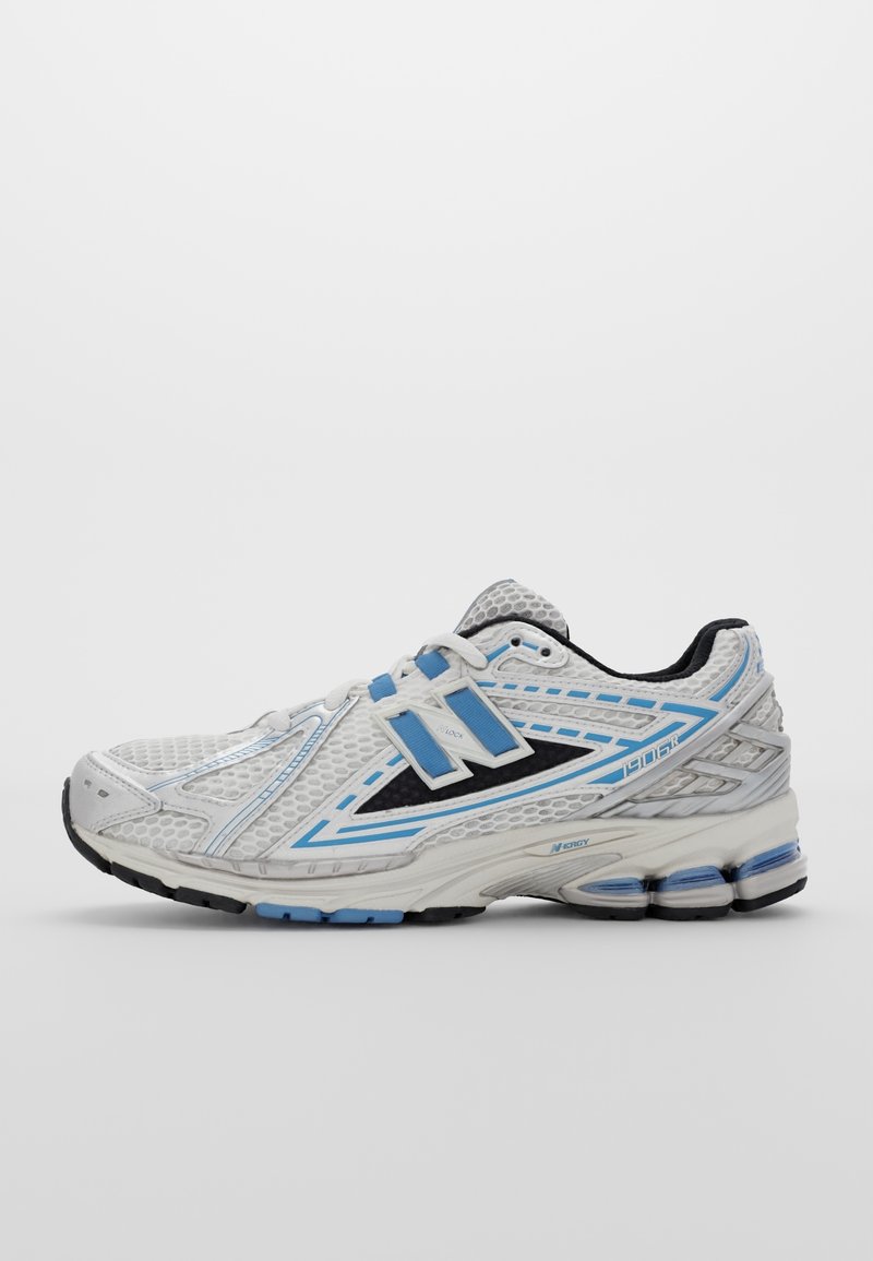 Chaussure de course blanche et bleue avec dessus en mesh, semelle épaisse rembourrée et deux bandes velcro sur le côté.