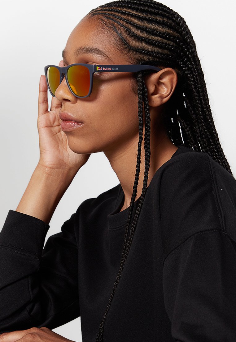 Okulary przeciwsłoneczne z ciemną oprawką i lustrzanymi pomarańczowymi soczewkami. Projekt charakteryzuje się smukłym kształtem i subtelnym brandingiem po boku.