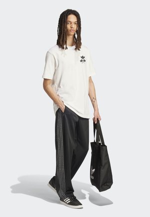 Λευκό βαμβακερό μπλουζάκι με μαύρο λογότυπο, μαύρο παντελόνι φόρμας με λευκές ρίγες και μαύρη τσάντα ώμου. Παπούτσια: μαύρα και λευκά αθλητικά παπούτσια.