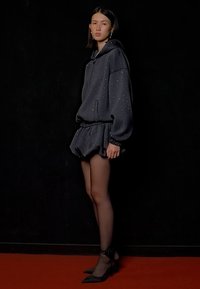 Sötétszürke kapucnis pulóver, csillogó díszítéssel, amelyet egy bővített szoknyával viselnek. Az öltözethez áttetsző fekete combig érő harisnyák és hegyes fekete magassarkú cipők tartoznak.