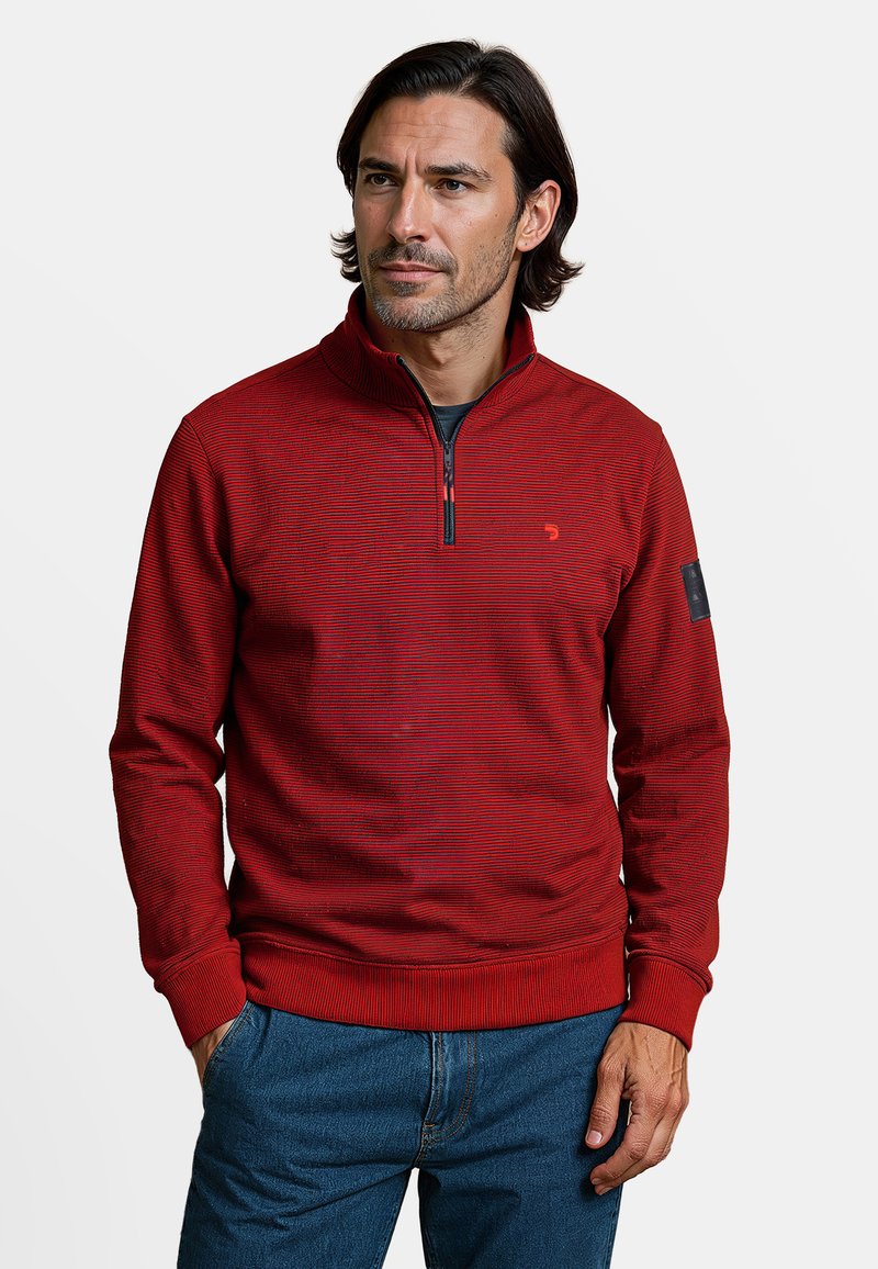 Rode ritstrui met een textuurpatroon, geribbelde manchetten en tailleband. Opvallend logo-detail op de linker mouw. Draag het over een zwart t-shirt.