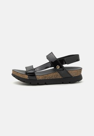 Sandalo in pelle verniciata nera con soletta in sughero, fascia regolabile, suola piatta in gomma e design minimalista.