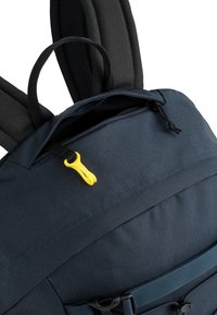 Marine rugzak met een gestructureerde stof, voorzien van een zwarte handgreep, een gele zipper pull en een verstelbare blauwe schouderband. Zichtbare stiksels als accent.