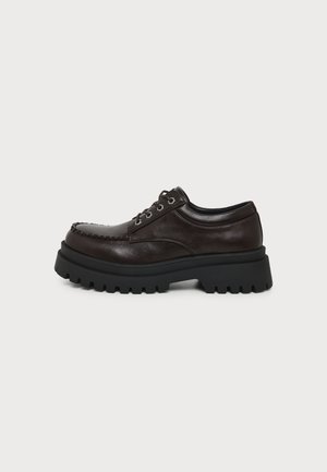 Chaussure en cuir marron foncé à lacets avec une semelle noire épaisse et robuste et couture style mocassin sur fond blanc.