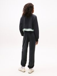 Klippe sort sweatshirt over en mint-stribet skjorte, parret med sorte joggers og hvide sneakers. Blød tekstur, afslappet pasform og elastiske manchetter.