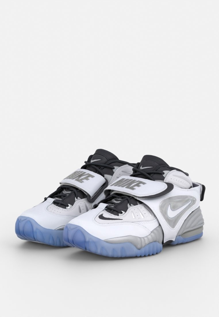Zapatos deportivos blancos y grises con detalles en negro, correas gruesas y un diseño de cordones. Presenta una suela texturizada en azul translúcido.