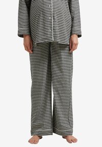 Black and white checkered pajama set with long sleeves and wide-leg pants, featuring button details and a soft cotton texture.