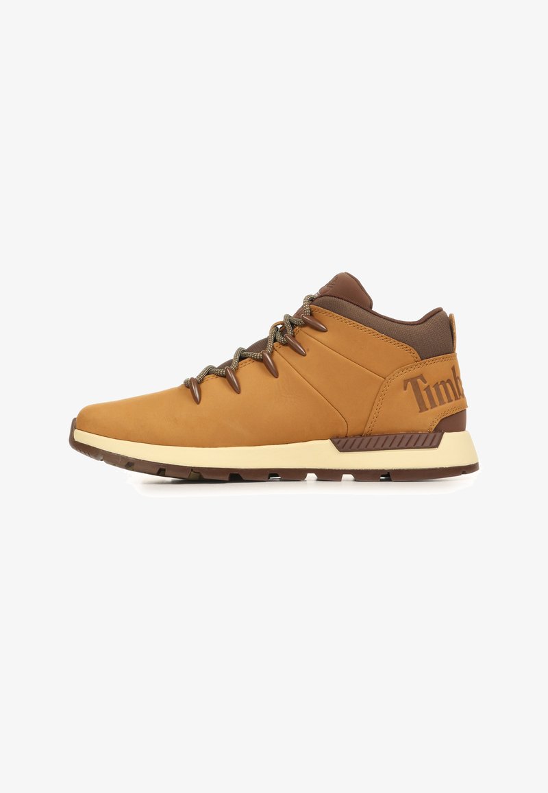 Chaussure de randonnée montante mi-hauteur marron et beige avec col rembourré, laçage avant, semelle épaisse crème, et marquage "Timberland" sur le talon.