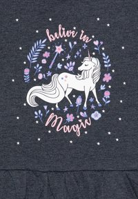 Pilkas audinys, kuriame pavaizduota vienaragis, supamas gėlių ir žvaigždžių, su tekstu "tikėk stebuklais" rožinės spalvos. Raukinėta apatinė dalis.