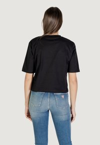 T-shirt nera cropped con maniche corte, realizzata in morbido cotone. Abbinata a jeans in denim azzurro chiaro con tasche posteriori e dettaglio del logo.