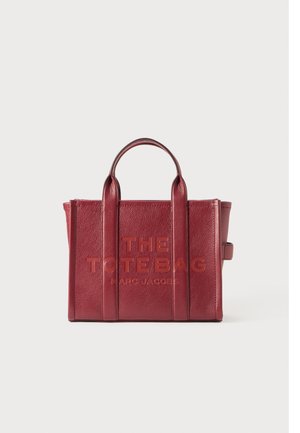 Rød læder tote taske med to håndtag og "THE TOTE BAG MARC JACOBS" præget på forsiden i midten.