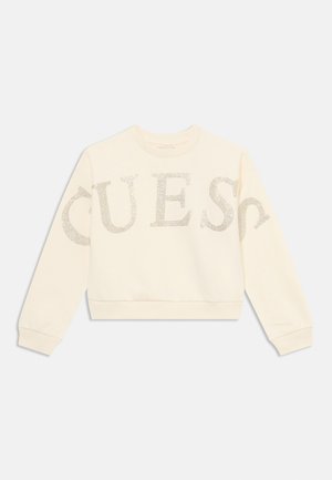 Kremowy sweatshirt wykonany z miękkiego materiału, z dużymi, błyszczącymi srebrnymi literami z napisem "QUEST" na przodzie.