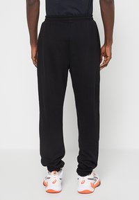 Czarne spodnie dresowe z elastycznym pasem i ściągaczami przy nogawkach. Wykonane z miękkiego materiału, mają luźny krój i minimalistyczny design.