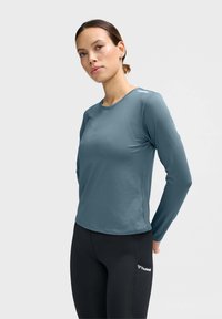 Sportieve lange mouwen top in gedempt teal, gemaakt van een gestructureerde stof, met een ronde halslijn en subtiele branding op de schouder.