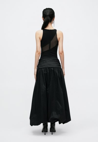 Robe noire avec un corsage ajusté orné d'accents en mesh et une jupe volumineuse et froncée. Tissu texturé à finition mate. Col montant.