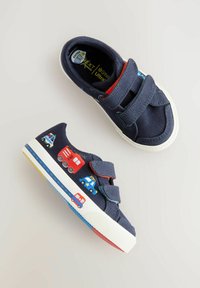 Navy canvas skor med dubbla kardborreband, prydda med färgglada broderade fordon. Vit gummisula med blå, gula och röda detaljer.
