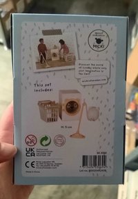 Speelgoedaccessoireset met een witte wasmachine met een deur met gouden accenten, een witte mand en een beige mop. Hoogte: 5 cm.