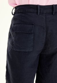 Pantaloni in lino blu navy con tasca laterale, tessuto testurizzato e vita standard con passanti per cintura.