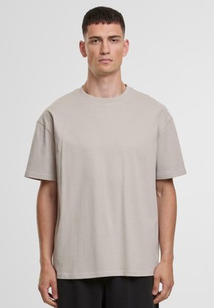 T-shirt beige clair à manches courtes en coton doux. Il présente un col rond et une coupe décontractée avec des détails de couture minimaux.