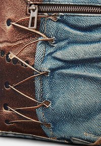 Tasche mit Denim-Print, ausgestattet mit einem Reißverschluss, strukturiertem Stoff, Braun- und Blautönen, sichtbaren Schnürdetails und Nahtakzenten.