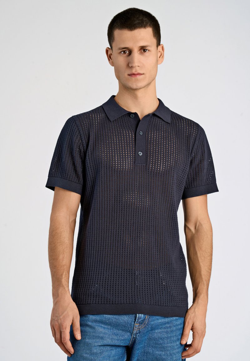 Navyblå perforerad kortärmad polo med krage, tre-knappsstängning samt ribbade mudd och fåll. Har en texturerad stickad design.