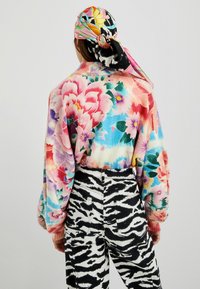 Suéter floral multicolor con mangas largas y puños acanalados combinado con unos jeans de cintura alta con estampado de cebra en blanco y negro.