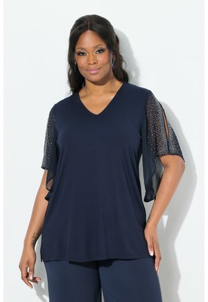 Navy blue top with a V-neck, short sheer sleeves adorned with silver studs, soft fabric, and a loose fit that drapes comfortably.