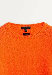 Pull en tricot orange avec un col rond. Présente un col côtelé et un tissu doux et texturé. Étiquette du fabricant visible à l'intérieur du col.