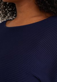 Námořnický pruhovaný pletený top s širokým výstřihem, který má strukturované horizontální pruhy a krátké rukávy pro přiléhavý siluetu.
