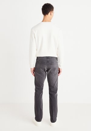 Lys grå jeans med rett passform, baklommer og minimale søm detaljer, kombinert med en hvit langermet skjorte.