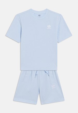 Hellblaues Adidas Waffelstrick-Shirt mit kurzen Ärmeln und passendem Shorts-Set, jeweils mit weißen Adidas-Logos auf der Brust und am linken Bein.