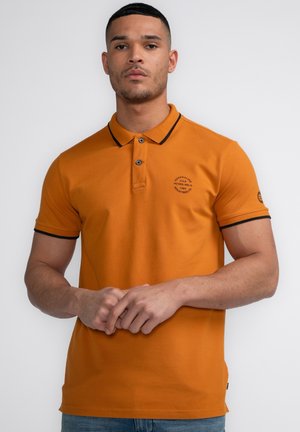 Polo orange avec des accents noirs, manches courtes, patte de boutonnage à deux boutons et un logo circulaire sur la poitrine. Finition en tissu lisse.