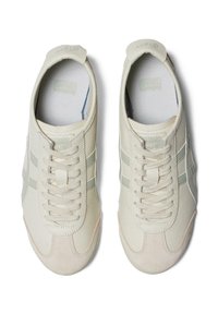 Jasno beżowe sneakersy z zamszowymi i teksturowanymi skórzanymi akcentami. Posiadają szare paski, płaskie sznurówki oraz wygodną wkładkę.