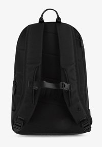 Fekete hátizsák párnázott pántokkal, texturált felülettel, állítható csattal, oldalsó cipzáras zsebekkel és egy finom logódíszítéssel az alsó jobb oldalon.