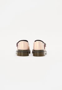 Scarpe in pelle rosa chiaro con forma arrotondata, dettagli neri e suola spessa e testurizzata marrone. Fibbia argentata di lato.