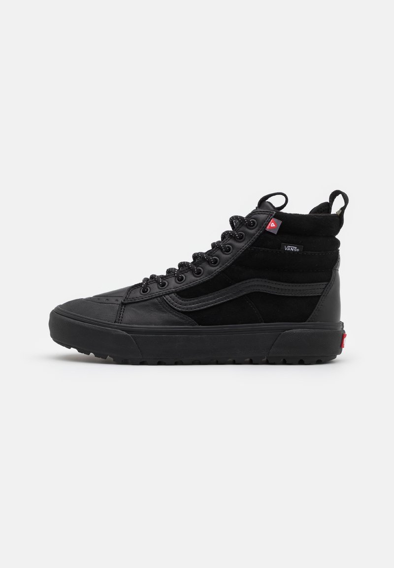Baskets montantes noires Vans avec lacets sur le devant, semelle en caoutchouc, et petites étiquettes rouges et noires du logo Vans sur le côté et au talon.