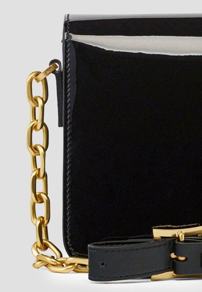 Schwarze Lederhandtasche mit glänzender Oberfläche, ausgestattet mit einem goldfarbenen Kettenriemen und einem abnehmbaren Schultergriff aus schwarzem Leder.