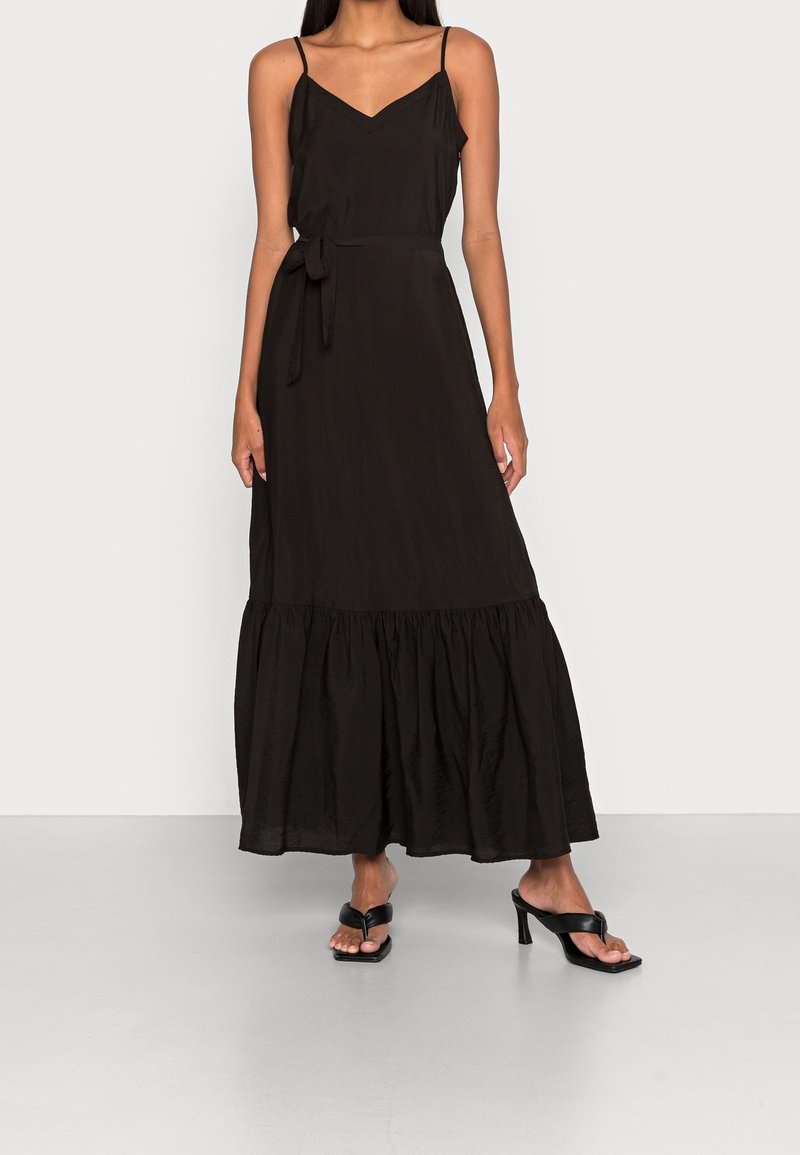 Černé maxi šaty s výstřihem do V, tenkými ramínky a páskem na zavázání v pase. Mají volánkový lem. Vyrobeny z lehkého materiálu.