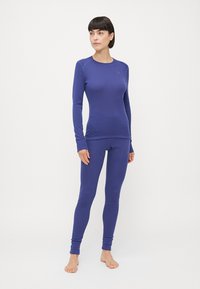 Violet aktivus drabužių komplektas, pasižymintis ilgomis rankovėmis marškinėliais ir legginsais, pagamintas iš glotnaus, elastingo audinio, su prigludusia forma ir lygiomis siūlėmis.