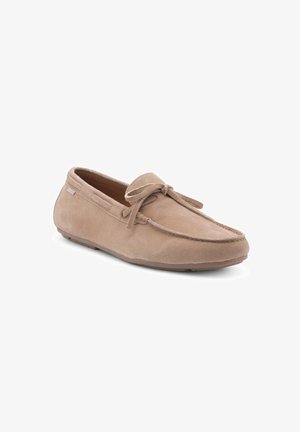 Mocassin en suède beige avec un bout rond, des lacets et une semelle en caoutchouc. Présente une couture le long des bords.