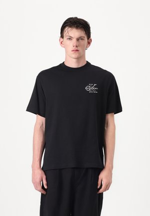 Fekete pamut póló kerek nyakkal, rövid ujjal, a bal mellrészen fehér Calvin Klein logóval. Egyszerű, laza szabású.