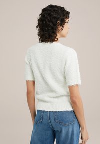 Kortärmad, strukturerad tröja i ljus mintgrön med en fluffig yta. Har en rundad halsringning och ribbad nederkant. Bärs med blåjeans.