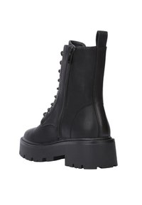 Bottines noires en cuir avec une semelle plateforme épaisse, un laçage à l'avant et une fermeture éclair sur le côté, présentant une texture lisse et un bout arrondi.