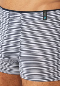 Striped boxer shorts in navy and white, made of a soft, stretchy fabric. Features an elastic waistband and a tailored fit.