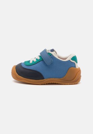 Blue and green sneaker featuring a mix of textile and synthetic materials, velcro strap, white laces, and a gum rubber sole.