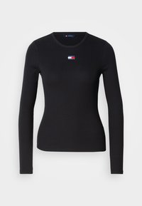 Maglietta nera a maniche lunghe con costine e collo rotondo. Presenta un piccolo logo colorato sul petto. Realizzata in un tessuto morbido ed elastico.