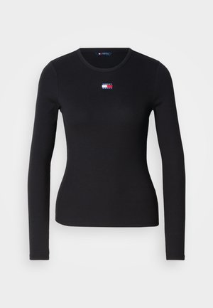 Maglietta nera a maniche lunghe con costine e collo rotondo. Presenta un piccolo logo colorato sul petto. Realizzata in un tessuto morbido ed elastico.