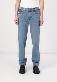 Jeans en denim bleu clair avec une coupe droite, cinq poches et un léger effet délavé. Fini avec un zip à bouton et des coutures contrastantes.