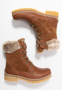 Botines marrones de cuero y ante, con un puño de pelo sintético, ojales de metal y una suela de goma resistente con un patrón de tracción.