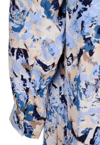 Šaty s dlouhým rukávem v abstraktním vzoru modré, béžové a námořnické barvy. Mají manžety na knoflíky a splývavou látku s texturovaným povrchem.